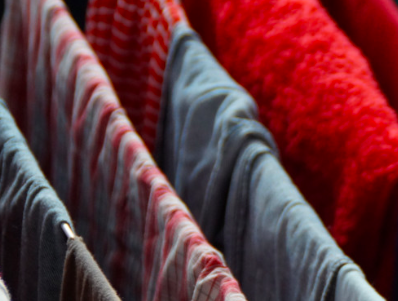 Clothes hanging indoors on a drying rack near a window during monsoon season, with natural light filtering in.